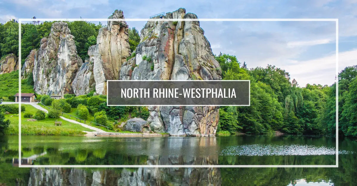 Tall rocky formations surrounded by greenery and a calm lake with reflections in North Rhine-Westphalia, Germany